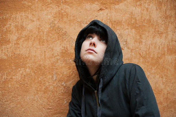黑暗的年轻女人悲伤地站在城市墙肖像附近