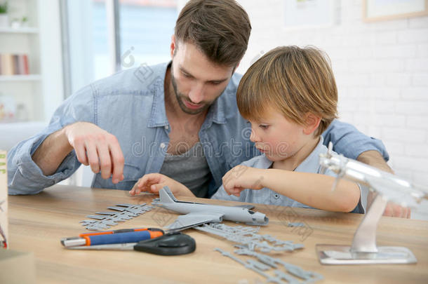 父亲帮助他的儿子建造一个飞机玩具