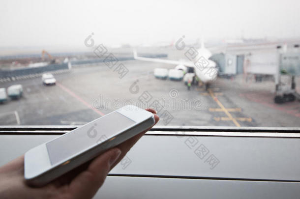 在机场的窗户边用智能手机