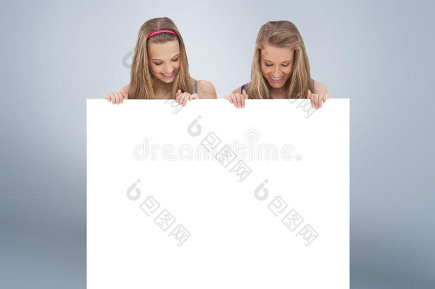两名年轻妇女抱着一块空白板特写的复合图像