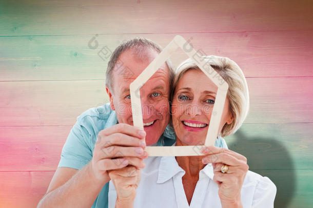 幸福的老年夫妇保持房子形状的复合图像