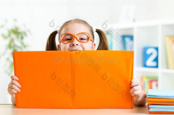 聪明的孩子小女孩在打开书后的室内