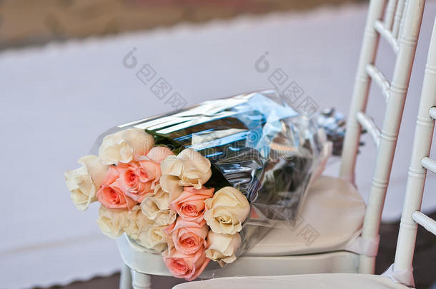 礼物玫瑰花束在婚礼地毯上椅子上的塑料包装纸上
