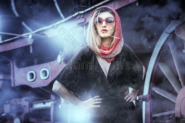 漂亮的女孩，戴着红头巾和太阳镜，在一辆<strong>老式火车</strong>前的站台上摆姿势。 女人的古董