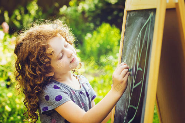女孩用粉笔<strong>在黑板上写字</strong>。 教育理念。 调色