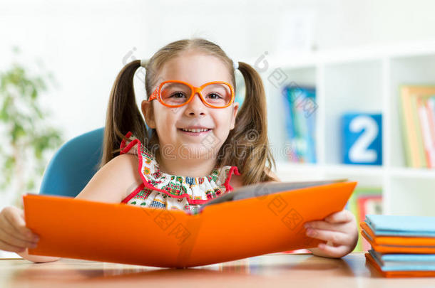 聪明可爱的小女孩用书把眼镜涂成黄色