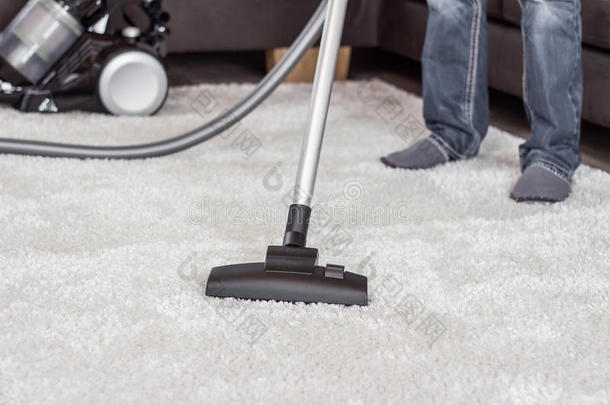 一个男人用吸尘器清洁地毯。