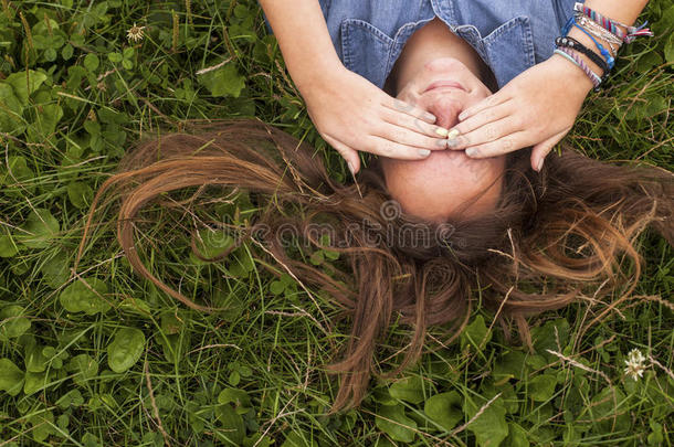 特写<strong>可爱</strong>的<strong>长发女孩</strong>躺在绿草地上。