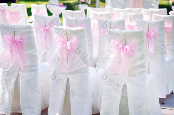 在椅子上装饰着粉红色的蝴蝶结，婚礼仪式