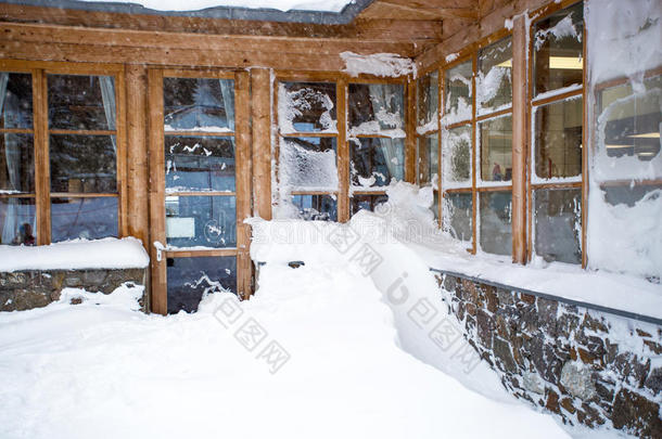 奥地利木屋，大窗户在暴风雪中被雪覆盖