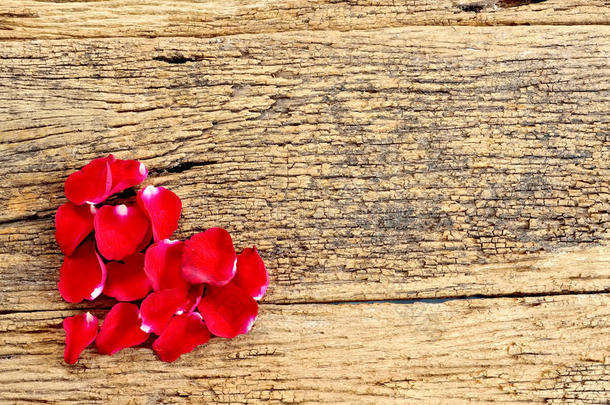 木制背景上红色玫瑰花瓣的美丽心灵