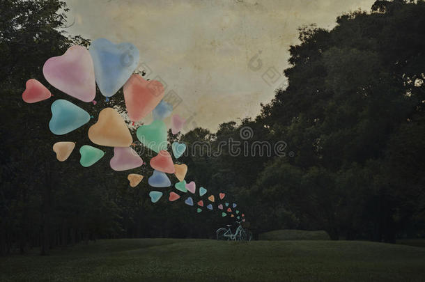 五颜六色的心爱气球漂浮在空中与自行车在公园