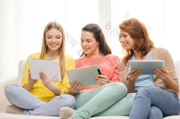 三个笑容满面的少女在家里拿着平板电脑