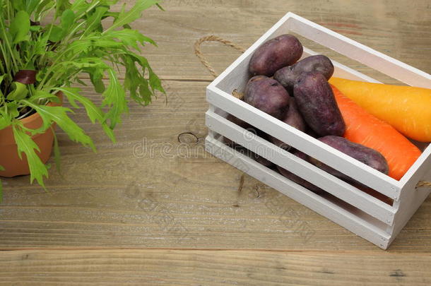 胡萝卜和土豆放在木制背景的盒子里