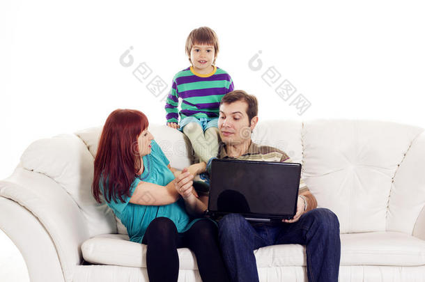 父亲、母亲和儿子坐在沙发上拿着笔记本