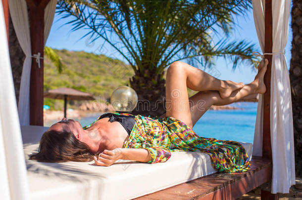 年轻漂亮的女人在沙滩床上放松