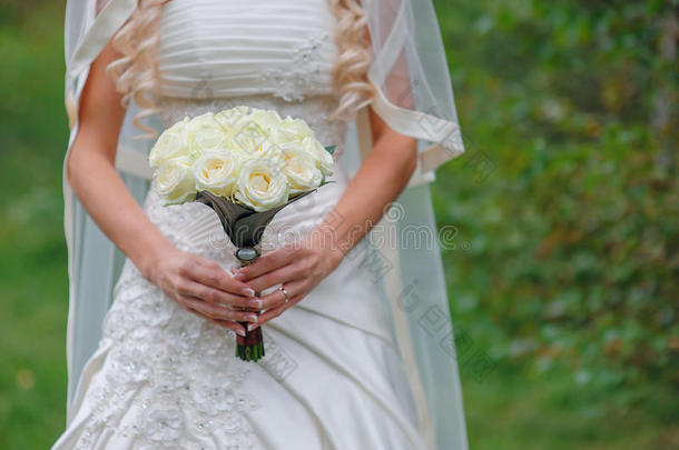 新娘手持白色结婚花束玫瑰和爱情花