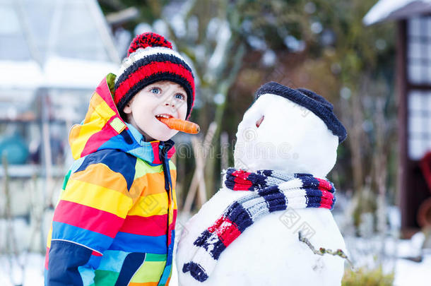 有趣的男孩穿着五颜六色的衣服在<strong>户外堆雪人</strong>