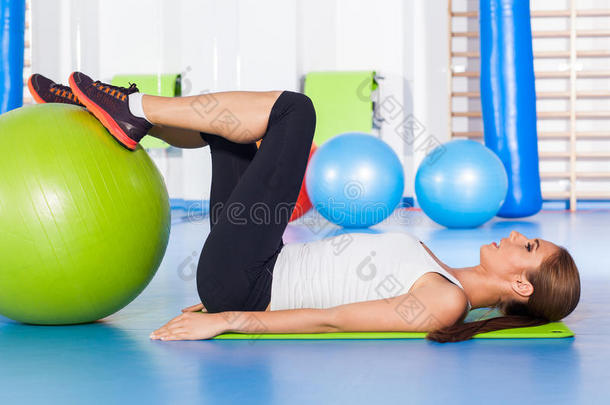 健身，运动，训练和生活方式的概念-妇女伸展和做体育锻炼与大绿色健身球在健身房
