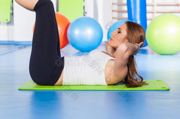 健身，运动，训练和生活方式的概念-妇女伸展和做体育锻炼的垫子在健身房