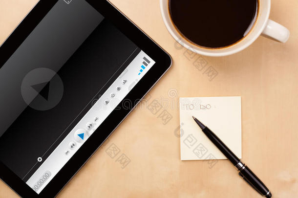 平板电脑在屏幕上显示媒体播放器，并打开一杯咖啡
