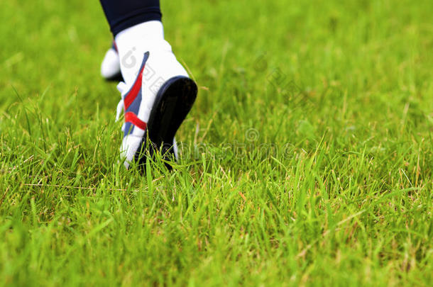 跑女人在绿草地上的脚步声。 跑鞋c