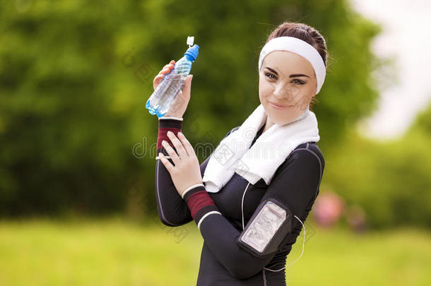 白种人的运动妇女在户外定期慢跑锻炼期间喝水。