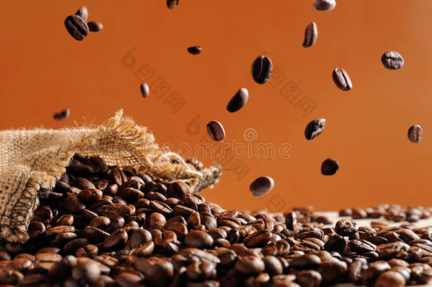 咖啡豆落在一袋咖啡豆和橙色背景上