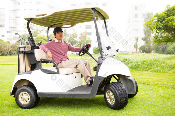 高尔夫球手驾驶他的高尔夫球车看着相机