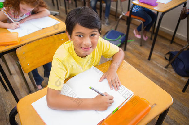 可爱的小学生在课桌前画画，一个对着镜头微笑
