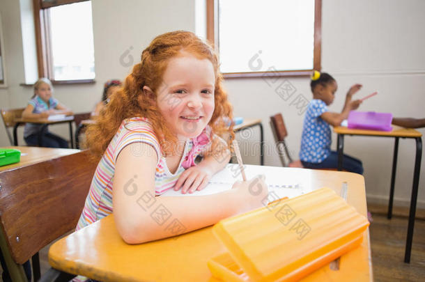 可爱的小学生在课桌前画画，一个对着镜头微笑
