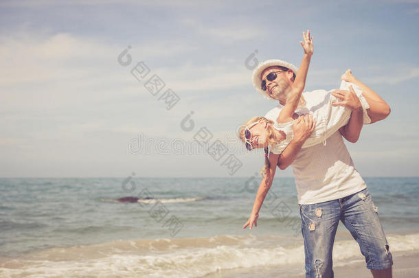 父亲和女儿白天在海滩上玩耍。