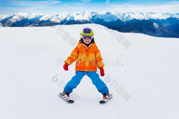男孩戴着滑雪面具和头盔在斜坡上滑雪