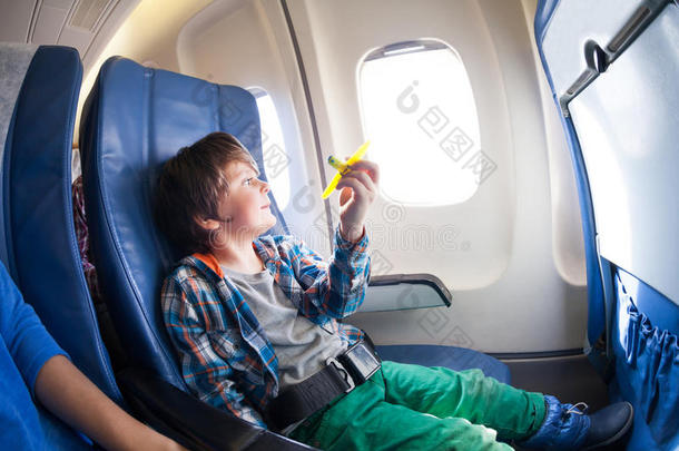 带玩具飞机的可爱男孩坐在飞机窗口旁边