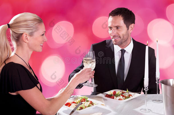 一对夫妇在餐厅的桌子上品尝香槟长笛