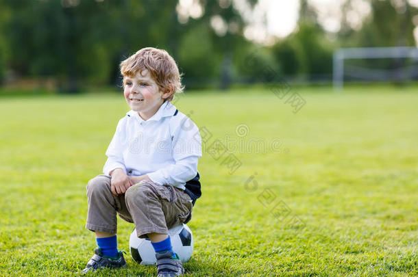 四岁的金发男孩在<strong>足球场上踢球</strong>休息