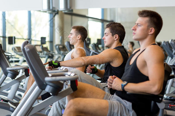 男人们在健身房骑着健身自行车锻炼身体