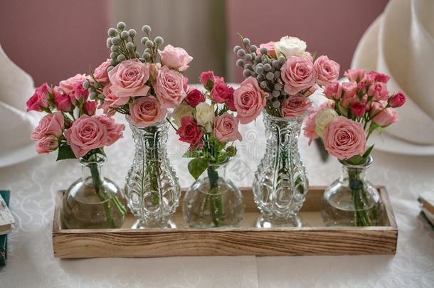 餐厅里喜庆的结婚桌上有五束玫瑰。 在水晶和玻璃花瓶里。