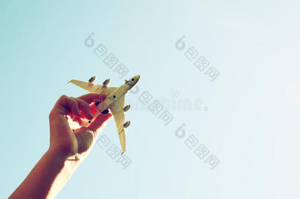 特写照片，女人的手拿着玩具<strong>飞机</strong>，对着蓝天和<strong>云彩</strong>