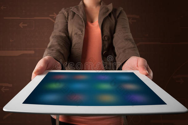 一个拿着白色平板电脑的女人，上面有模糊的应用程序