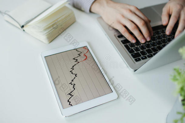 沮丧的商人用坏的股票市场图表打字笔记本电脑