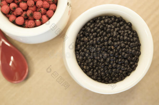 黑色扁豆和红色浆果在一个瓷杯关闭