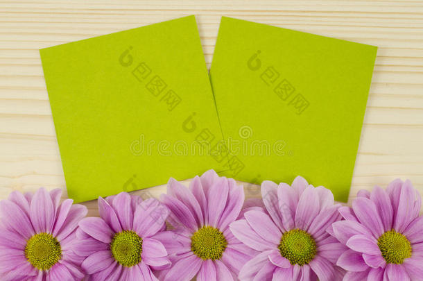 木制背景上的空白绿色卡片和粉红色花朵