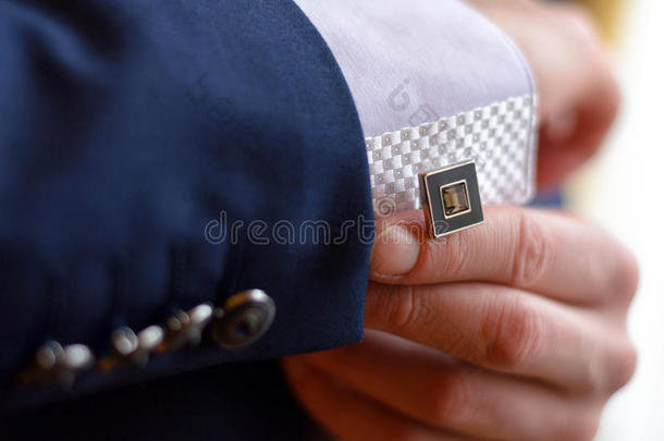 一个人系着一个袖口链扣
