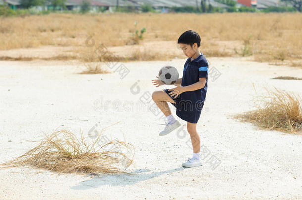 男孩在干土地上<strong>踢</strong>足球