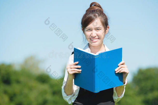公园里的亚洲学生带着书和讲稿