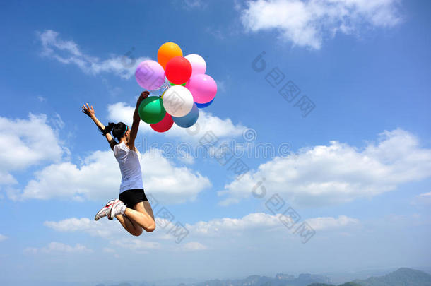亚洲女人用<strong>彩色</strong>气球在山顶<strong>岩石</strong>上跳跃