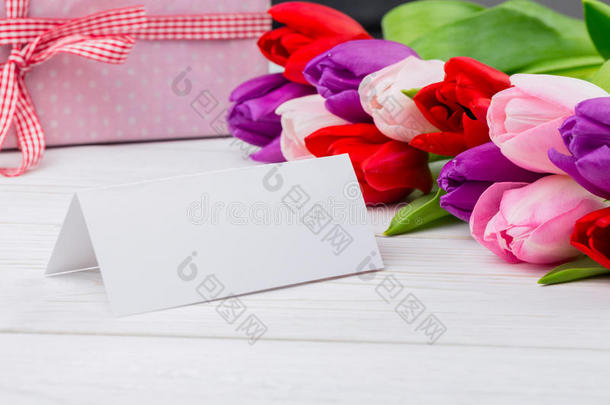 五颜六色的郁金香和白色的卡片，后面有礼物