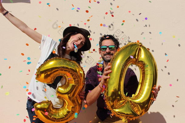 欢快的夫妇用大的金色气球庆祝三十年的生日