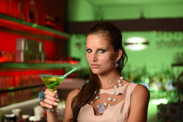 年轻漂亮的黑发女人在酒吧里喝鸡尾酒
